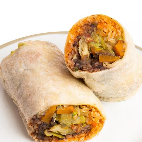 Two Indian curry burritos, one whole and one cut in half, revealing rice, vegetables, and beans.
